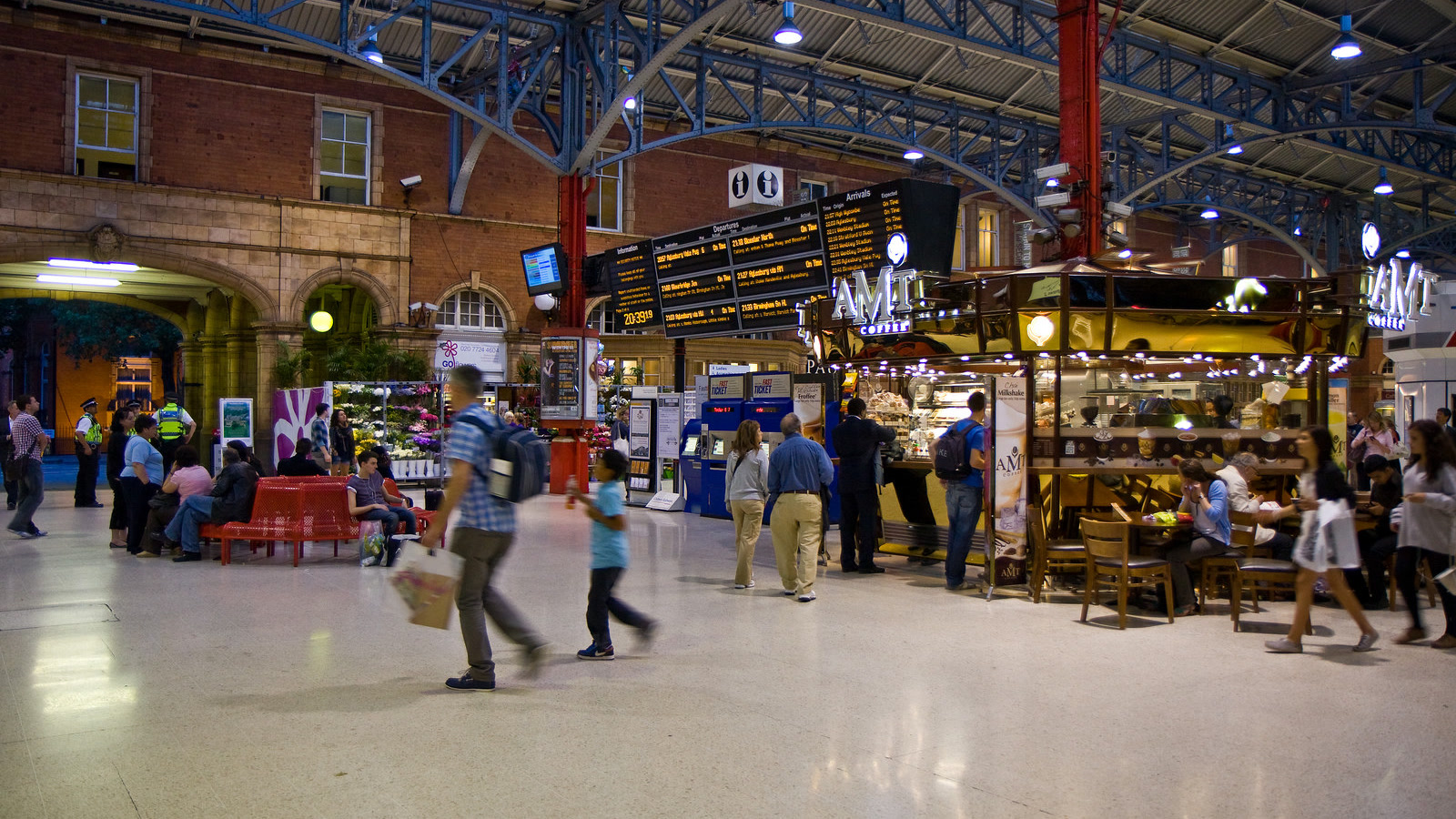 Passengers and coffee kiosk beneath the arched roof of London Marylebone railway station concourse.